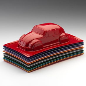 Vacuum-formed thermoplastic: red sheet moulded into a detailed car relief on a stack of flat coloured sheets